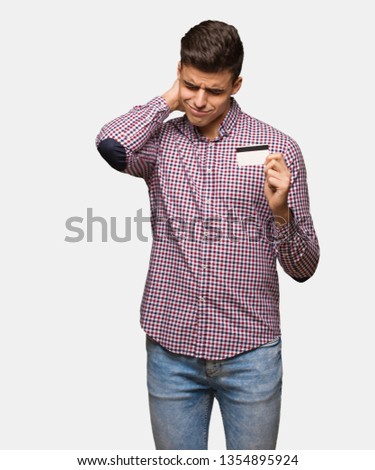 Young man holding credit card suffering neck pain