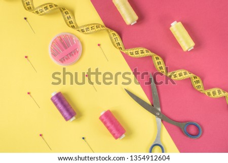 Bright yellow and pink background with contrasting sewing supplies and accessories for needlework