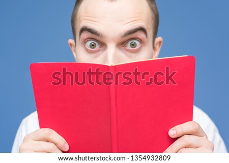 Guy reads the book, stares in surprise at the camera, close up, background, copy space, for advertising