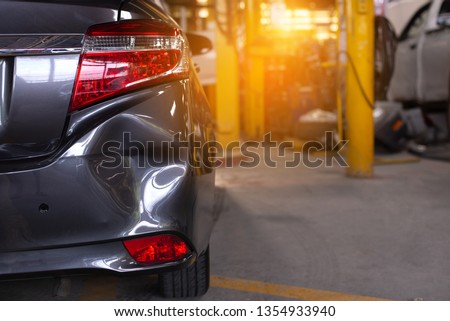 Close up of the rear bumper dent of a grey car in preparation of repair work,Make the surface of the car smooth ,preparing for painting at station service. Royalty-Free Stock Photo #1354933940