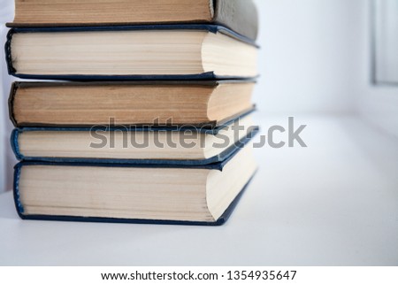 A stack of books on a white table. Collection for study.