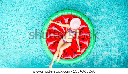 Young woman relaxing on watermelon lilo in villa resort pool - Rich girl floating with fruit mattress drinking tropical cocktail - Summer holiday, luxury lifestyle and fashion concept