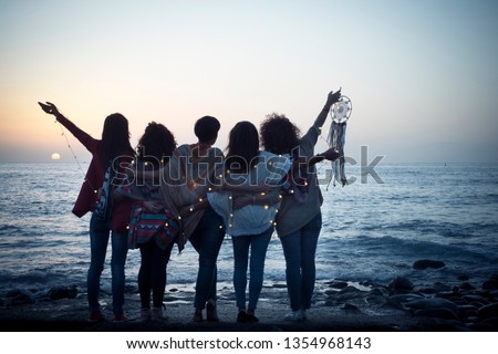 Romantic and dreamer concept image with five friends women hug each other viewed from back looking at the sunset holiding light - love freedom and wanderlust for group of people