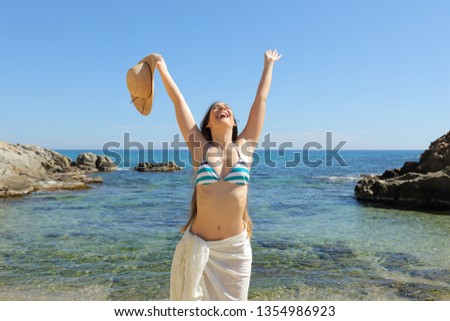 Happy tourist raising arms celebrating vacation on a beautiful beach on summer