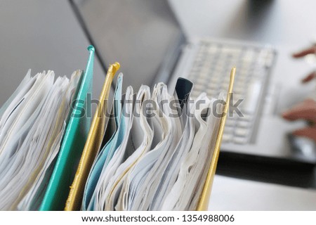 Hands of parson typing on laptop computer with binders in foreground. Selective focus