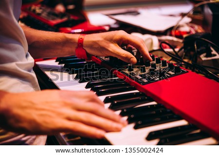 Playing music using an analog synthesizer connected to a modular synthesizer. Electronic music and professional music equipment concept. Royalty-Free Stock Photo #1355002424