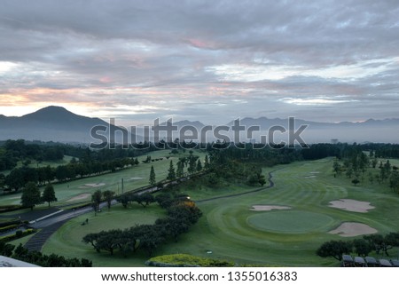 Green golf field and blue cloudy sky