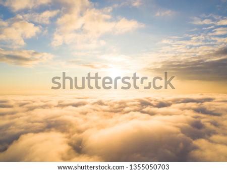 Aerial view White clouds in blue sky. Top view. View from drone. Aerial bird's eye. Aerial cloudscape. Texture of clouds. View from above. Sunrise or sunset over clouds