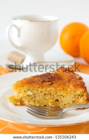 Orange pie on white plate with a cup of tea and oranges