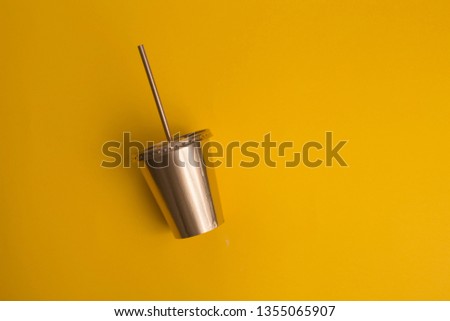 Gold painted drinking cup on yellow background