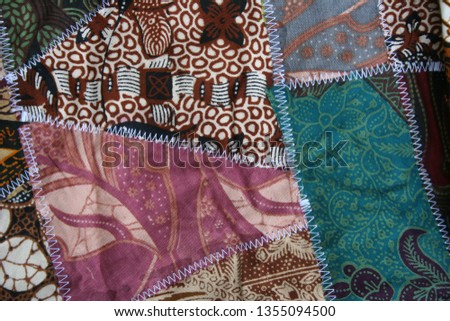 Batik material background, Indonesian material pieced together with white zigzag stiches in crazy quilt design in colorful blue green pink and brown colors Royalty-Free Stock Photo #1355094500
