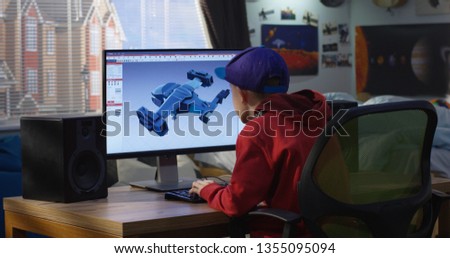 Medium shot of a boy using a computer to design a futuristic airplane at home