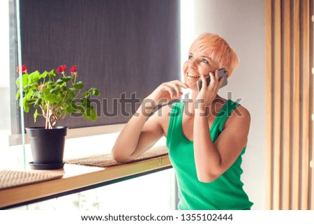 Happy young woman relaxing at home chatting with her touch screen smartphone. People and technology concept