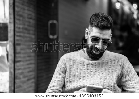 Latin Man Wearing Sunglasses Using a Cellphone in a Terrace Cafe Outdoors - Using a Phone While Having Breakfast. Lifestyle Concept.