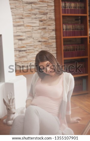 Portrait of pregnant woman holding her belly,sitting on floor.