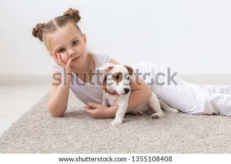 Childhood, pets and dogs concept - Little child girl posing on the floor with puppy