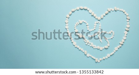 Silhouette of the embryo (child) of people in the heart of white tablets on blue background. Treatment of newborns, medical care.