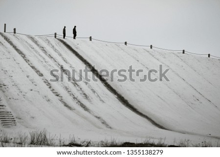 A huge snow slide. Two figures. Winter .. Picture taken in Ukraine. Kiev region. Horizontal frame. Color image. Tint
