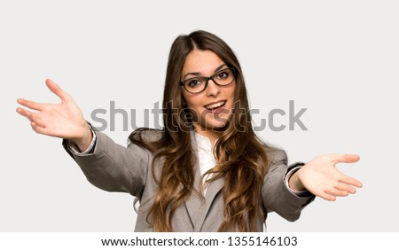 Business woman presenting and inviting to come with hand over isolated grey background