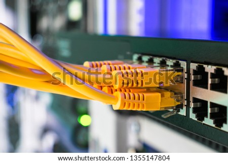  Information technology concept.  Utp cable connects to the interfaces of the main office router. Many yellow internet wires connect to the network switch in the server room. 