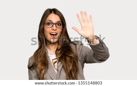 Business woman counting five with fingers over isolated grey background
