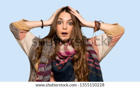 Young hippie woman takes hands on head because has migraine over isolated blue background