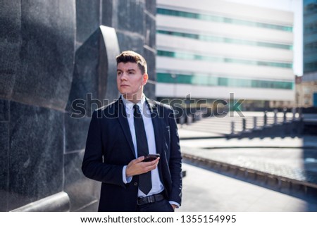 Young businessman well dressed using smartphone at city