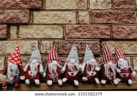 Seven gnomes, dwarfs seating against brick wall.