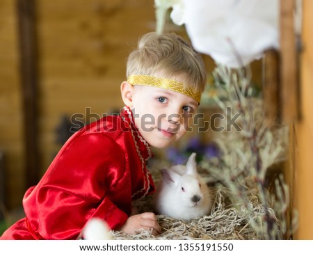 little boy plays with white Easter Bunny. on the green grass and baby bunnies, Spring Festival and birth. living Easter rabbits.