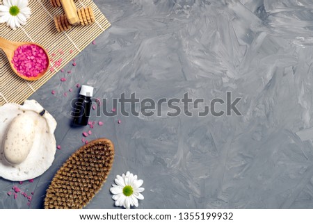 Organic spa cosmetic and products on grey stone background. Spoon with pink bath salt, body brush, organic soap, and flowers. Top view, flat lay, copy space.  Banner template for spa salon. 