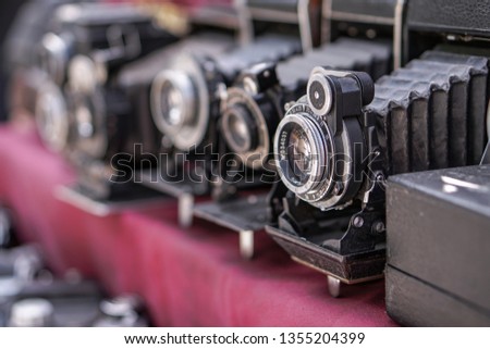 Vintage retro photo equipment at a flea market. Film photo camera on a red background. Stock photography, photo.