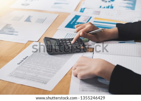Business woman using calculator and laptop for do math finance on wooden desk in office and business working background, tax, accounting, statistics and analytic research concept