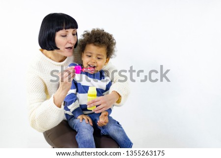 Happy mom plays with her little son, they blow bubbles and have fun. Happy multiracial family.