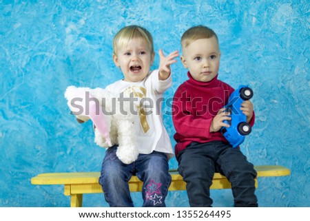 Little kids with toys on blue background. Happy childhood. Emotional portrait of young children.
