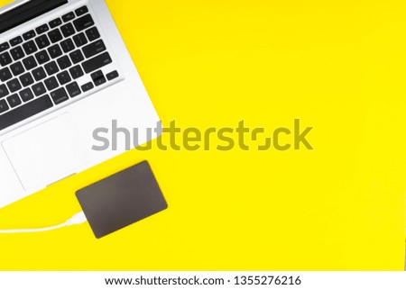 Laptop keyboard, storage drive or hard disk on yellow background with selective focus, crop fragment, business, backup, copy space concept.