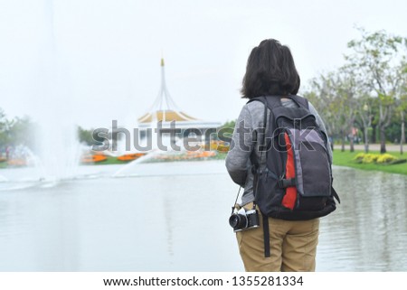 A woman carrying a camera, traveling tourists, walking around the park