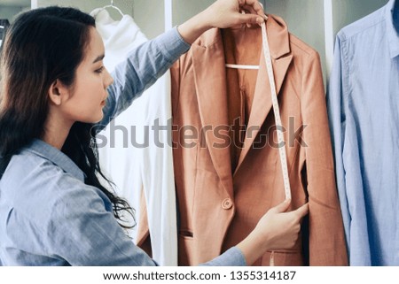 Young fashion designer women working taking measurements garment on working desk in her studio. professional dressmaker fashion concept.