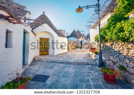 Tourist take picture of strret with trullo (trulli) -  traditional Apulian dry stone hut with a conical roof. Splendid spring cityscape of Alberobello town, province of Bari, Apulia region, Italy.