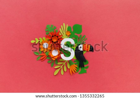 letter S of the alphabet cut out of white paper, surrounded by tropical flowers. Pink background. Lettering postcard. Handwork. Paper craft.