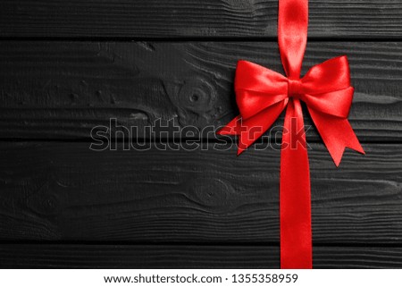 Red bow and ribbon on wooden background