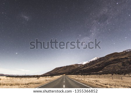 Center of the road in the Mt Cook National Park with the Milky Way above the mountains at night time.