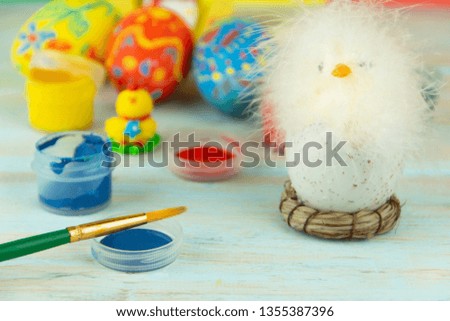 Easter eggs on multicolor wooden background with baby chicken, paints and brush