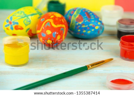 Close-up paints and brush on multicolor wooden background with Easter eggs Easter crufts