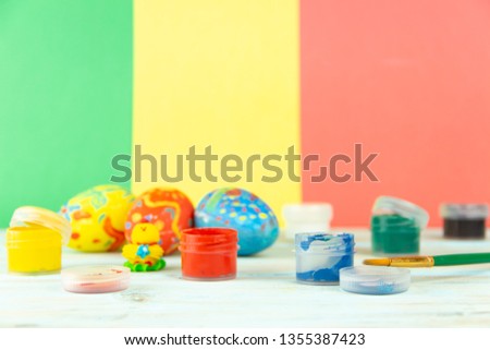 Handmade Easter eggs on multicolor wooden background with paints and brush