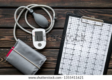 cardiologist work desk with pulsimeter and cardiogram on wooden background top view