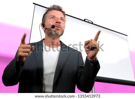 young attractive and confident successful man with headset speaking at corporate business coaching and training auditorium conference room talking giving motivation training from speaker stage