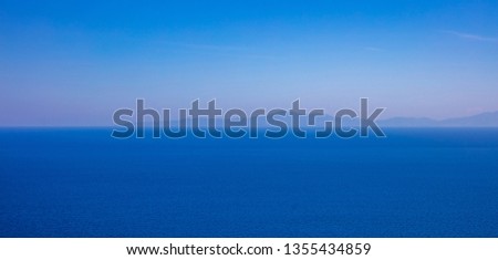 Greece. Aegean sea, blue shades. Blue clear sky and calm sea. Mountain silhouettes in blue pastel color, banner