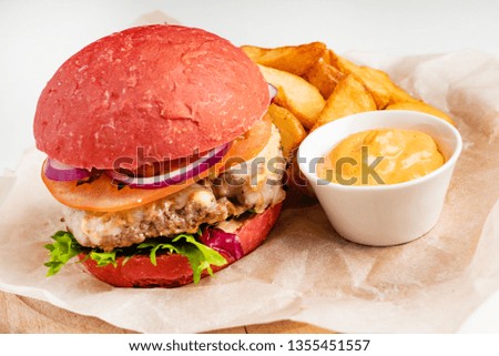 red burger with roasted potatoes and sauce