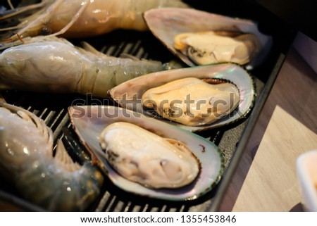 Fresh raw shrimp and mussel on black tray ready to cook
