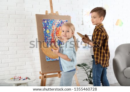 Cute little children painting on easel at home